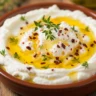 Close-up of creamy hot honey ricotta dip with thyme and red pepper flakes.